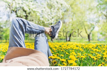 Relaxing woman lying on spring blooming meadow. Girl resting in summer park. Enjoy life, having fun, leisure, relaxation, lifestyle concept