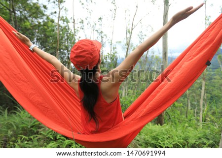 Relaxing woman outstretched arms in hammock in summer rainforest mountain top