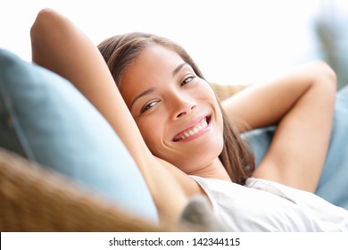 Relaxing woman sitting comfortable in sofa lounge chair smiling happy looking at camera. Resting beautiful young multicultural asian caucasian girl in her 20s . - Powered by Shutterstock