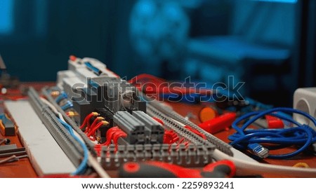 Relay with electromagnetic coils of direct and alternating current, red wires with yellow bushing ferrules, blue cord. Automatic electrical switch in an electrical workshop. Close up.