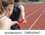Relay race handing over from woman to man. Unfiltered version