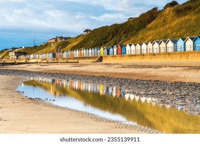 Relections of the beach huts on the beach at Mundesley in North Norfolk, UK at Sunrise