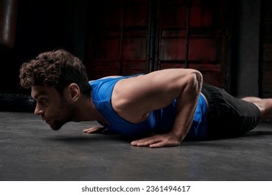 relentless man in blue tank top doing push-ups while working out on city street at night - Powered by Shutterstock