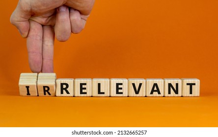 Relevant or irrelevant symbol. Businessman turns wooden cubes changes the word irrelevant to relevant. Beautiful orange table orange background. Business, relevant or irrelevant concept. Copy space.