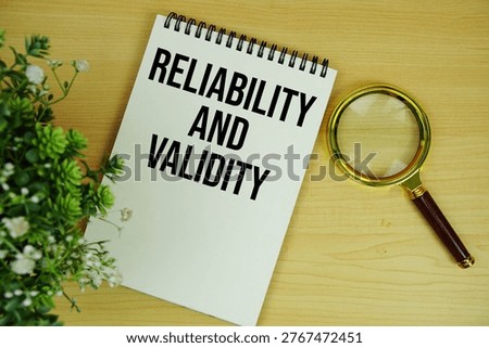 Reliability and Validity text written on notepad with magnifying glass flat lay on wooden background