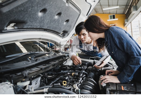 Reliable auto mechanic\
talking to a female customer the engine error in a modern\
automobile repair shop