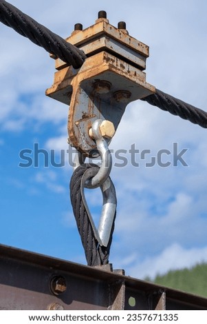 Reliable strong metal cable with connecting fastening with bolts and nuts of different sizes, outdoors. metal loop with steel wire as part of a bridge
