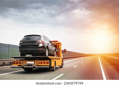 Reliable Towing and Recovery Services. Assistance for Vehicle Breakdowns and Accidents. Emergency roadside assistance on the highway. side view of the flatbed tow truck with a damaged vehicle