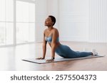 Relief Lower Back Pain. Smiling Sporty Woman Doing Sphinx Cobra Pose Or Upward-Facing Dog Asana Stretching Back Muscles Practicing Pilates, Excercising At Fitness Studio Or In Living Room On Yoga Mat