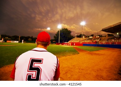 Relief pitcher watching his team play baseball at night - Powered by Shutterstock