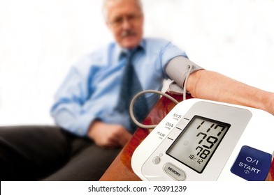 Relieved Senior Man In Shirt And Tie (businessman Or Teacher) With A Low Blood Pressure Reading On The Monitor. On White.