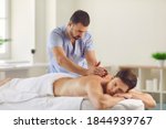 Relieving back muscle tension. Professional masseur massaging young man