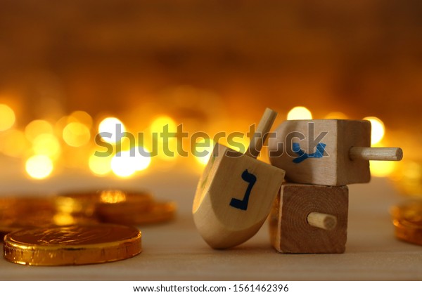 religion concept of of jewish holiday\
Hanukkah with wooden dreidels (spinning top) and chocolate coins\
over wooden table and bokeh lights\
background