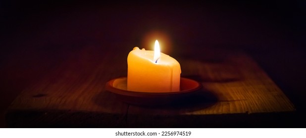 Religion concept.Light candle on old wooden background in church.Candlelight on vintage wood table christianity study and reading in home.Religious concept.Dark background.Banner.