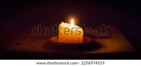Religion concept.Light candle on old wooden background in church.Candlelight on vintage wood table christianity study and reading in home.Religious concept.Dark background.Banner.