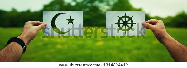 Religion conflicts as global issue concept. Two\
hands holding different faith symbols, Islam vs Buddhism belief\
over green field nature. Relationship between different people\
doctrines and creed.