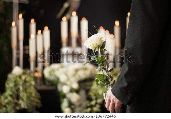 Religion, death and dolor  - man at funeral with
white rose mourning the
dead