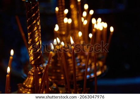 Religion and magic. Candles are burning in a dark church. In the background is a mysterious dim light and an old chandelier