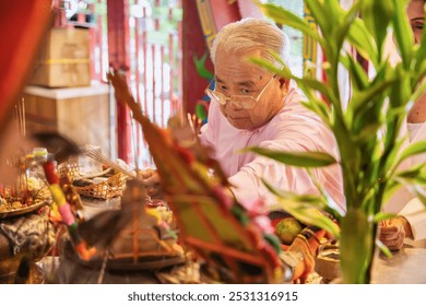 Religious Asian senior man pray and light up joss stick incense. Asian old man burning incense joss stick with flame for pilgrim, religious service in shrine, temple or monastery - Powered by Shutterstock