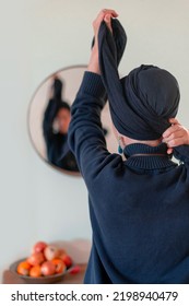 Religious Jewish woman puts a shawl on her head in front of a mirror. Back view (25)