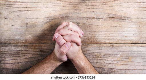 Religious man crossed hands in prayer on desk. Praying hands of a man on wooden table - Shutterstock ID 1736133224