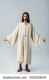 religious man in jesus robe standing with outstretched hands on grey