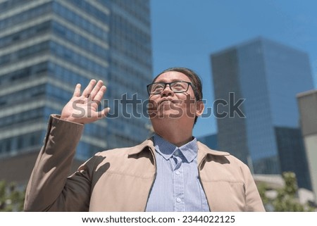 A religious man looks up to God above making a pact or solemnly swears the truth and makes a promise. A pious attorney with a clean conscience taking an oath. Outdoor city scene.