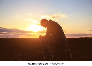 Religious Man Praying Outdoors At Sunset