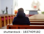 Religious middle age man praying and meditating in catholic church. Person begging for forgiveness and blessing from God. Catholicism is Christianity religion.