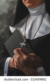Religious nun in religion concept against dark background.close-up of hands holding a bible and cross