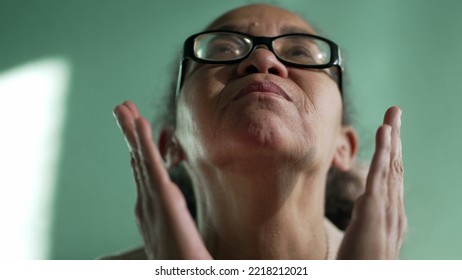 Religious Older Senior Hispanic Woman Praying To God. Spiritual South American Female Senior Person Looking Up Closeup Face In Prayer