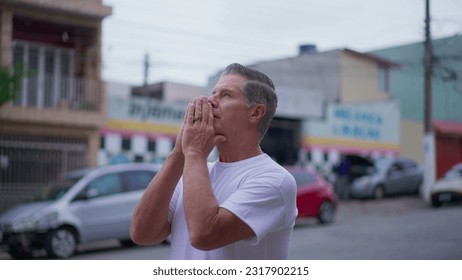 Religious Senior man standing on street in Prayer. Devoted middle-age male caucasian person Praying to God looking at sky smiling exuding HOPE and FAITH - Powered by Shutterstock