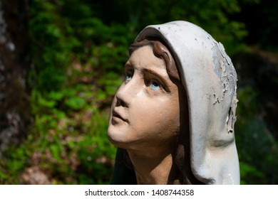 Religious statue of Bernadette Soubirous. Female worshipper and prayer is looking up the God or Virgin Mary. Woman and girl  is praying. Unfocused background.