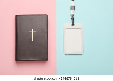Religious volunteering, messianism. Bible with cross and id card on string, pink blue background