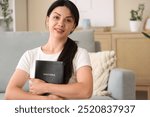 Religious young woman with Holy Bible at home