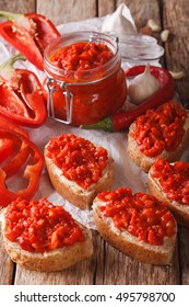 Relish (Ajvar) of Roasted Red Bell Peppers on toast slices close-up on the table. Vertical