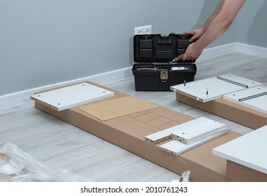 Relocation And Assembling Furniture Concept.Unpacking A Cardboard Box With Furniture.Assembly Of New Furniture In Apartment By Owner.