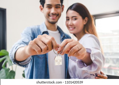 Relocation and beginning new life. Asian couple showing keys apartment after purchase and moving in new room together.