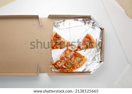 The remaining pizza is in the box. Empty pizza box with three slice remains. Top view