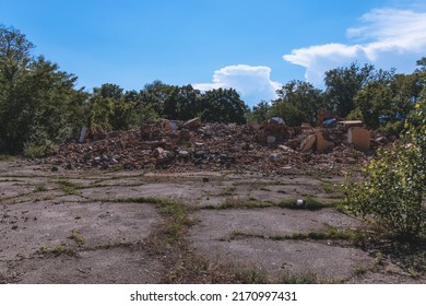 Remains Of A Destroyed House. Damaged Red Bricks. Rubbish Building Mountains. The Ruins Are Isolated, Small Fragments Of Concrete Stacked Like Mountains From The Demolition Of The House