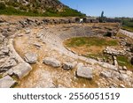 Remains of Roman theater located on hillside in ancient settlement of Limyra in Antalya province of Turkey. View of stone seats of semicircle auditorium descending towards ruined stage..