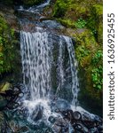 Remarkable Lower Little Mashel Falls cascading into a moss covered rocky surface leading to a small pool of water in the creek at the Charles Pack Forest during the summer in Pierce County Washington 