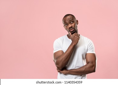 Remember all. Let me think. Doubt concept. Doubtful, thoughtful afro man remembering something. Young emotional man. Human emotions, facial expression concept. Studio. Isolated on trendy pink. Front
