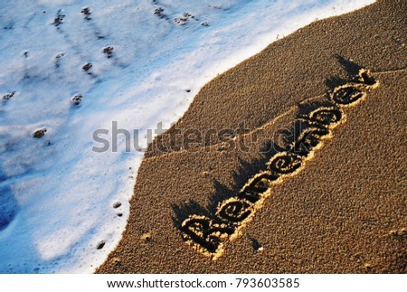Remember handwritten on sandy beach with soft ocean blue wave on background