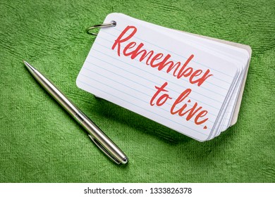 Remember To Live Reminder - Handwriting On An Index Card With A Pen Against Green Textured Paper