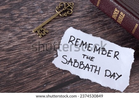 Remember Sabbath Day, handwritten Christian text note with holy bible and antique key on wooden table. Obedience, worship, rest on the seventh day, biblical concept.
