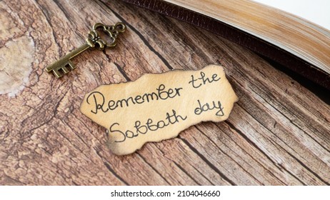 Remember Sabbath Day Handwritten Quote On Ancient, Old-fashioned Paper, Vintage Rustic Key, And Holy Bible Book On Wooden Table. Christian Biblical Concept Of Fourth Commandment From God Jesus Christ.