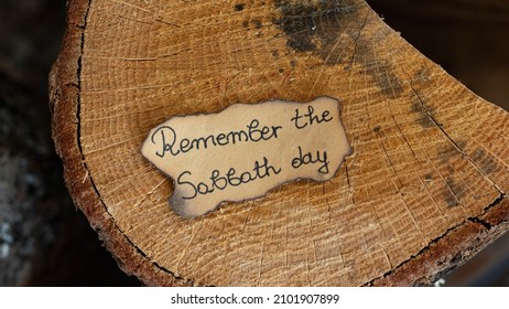 Remember The Sabbath Day Text Quote Handwritten On Old Paper On An Oak Wooden Log. Top Overhead View. The Biblical Concept Of Rest, Keeping The Fourth Commandment For Seventh Day Sabbath Holy.