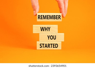 Remember why you started symbol. Concept word Remember why you started on wooden block. Beautiful orange table background. Businessman hand. Business remember why you started concept. Copy space.