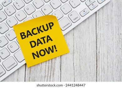  Reminder to backup data now with white computer keyboard on weathered wood desk